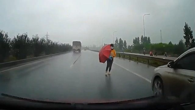 [動画0:15]傘をさして高速道路を渡る女性、はねられる