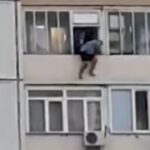 [動画0:14] 窓枠に座る男性、背中を押されて落とされる