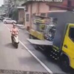 [動画0:56] スクーターの女性が路駐トラックのリフトで転倒！隣のトラックに頭を轢かれる