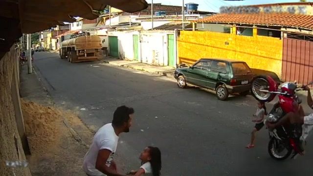 [動画0:30] 道路に飛び出す少女、後輪走行のバイクに吹っ飛ばされる