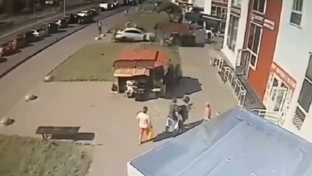 [動画0:21] 屋台で賑わう広場、女性の運転する車が暴走して歩行者を轢く
