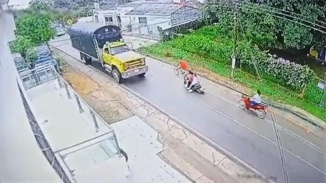 [動画0:13] 母と娘の乗るバイクが転倒、大型トラックの下にダイブしてしまう