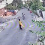 [動画0:09] よく確認せずに道路を横断する女性、バイクの直撃をくらう