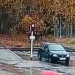 [動画0:15] ヘッドホンにフードの男性、列車に気付かず踏切を渡ってしまう