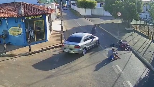 [動画0:59] 車に衝突して道路に投げ出されたライダーさん、膝を抱えて座り込む