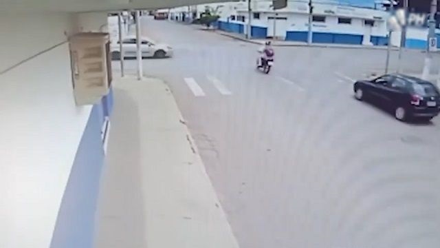 [動画0:19] バイクが信号無視の車に衝突、道路に投げ出される男女