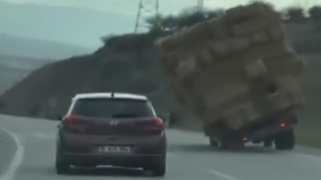 [動画0:23] 干し草積み過ぎトラック、走行中に倒れる